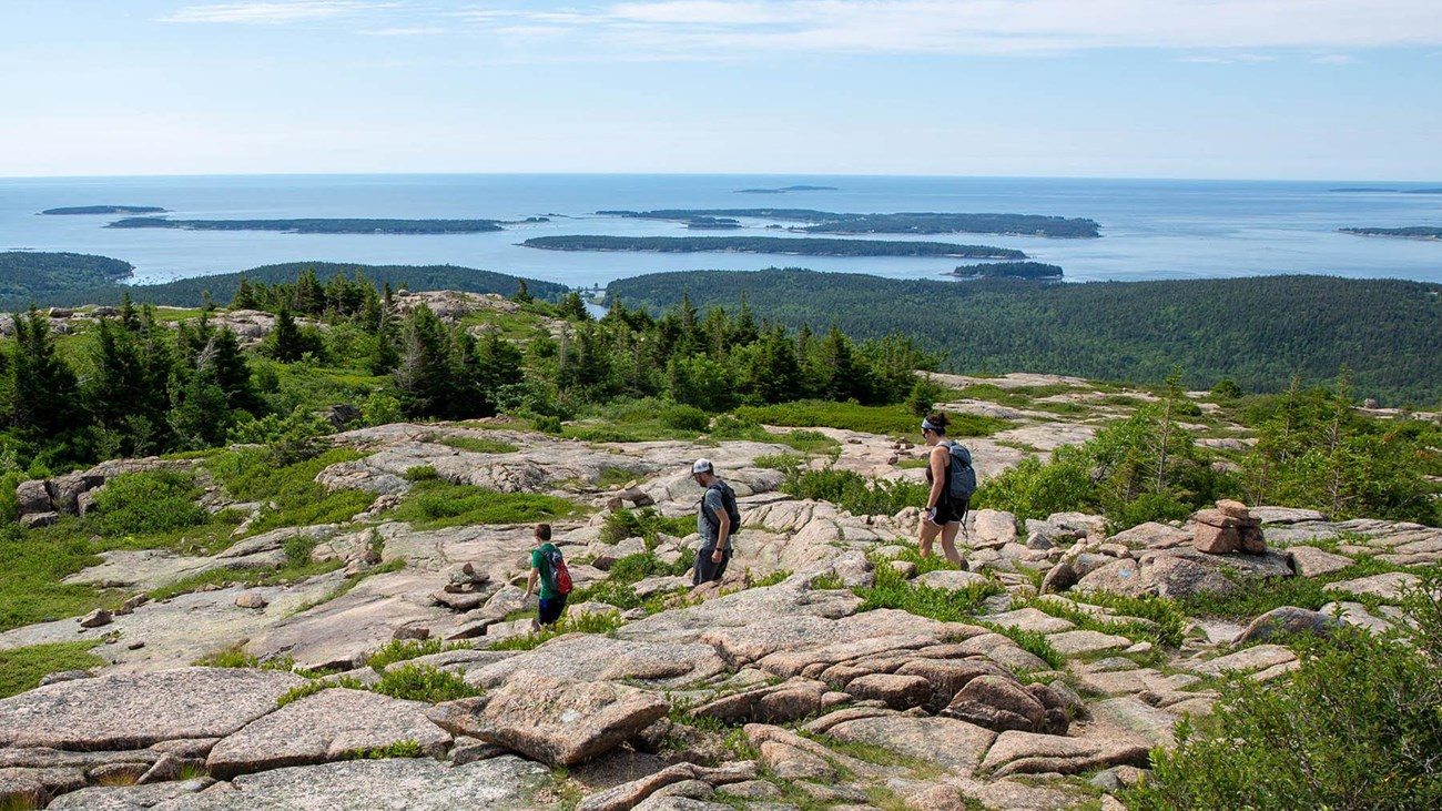 Family hiking open granite high above Mount Desert Island